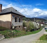 Unusual properties in Heľpa, an older house by a country road, hills in the background.