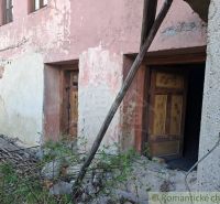 An older building with a neglected facade and wooden doors in Heľpa, unusual properties.