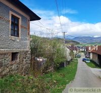A street in the village of Heľpa with unique properties and a view of snow-covered hills.