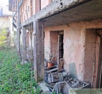 An abandoned building among peculiar properties in Heľpa with a damaged facade and an unkempt garden.