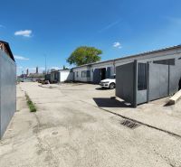 Industrial area with warehouses and halls in Trnava, visible parking lot and gates.