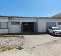 A white warehouse and hall building in Trnava with a car in the parking lot.