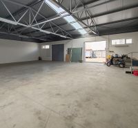 Interiors of warehouses and halls with concrete floors, skylights, and open doors.