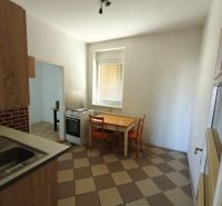 A kitchen in a family house with a white stove, a table, and orange chairs.