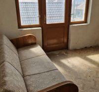 A room in a family house with a sofa and large windows with a view.