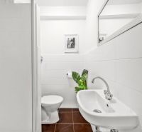 Bathroom of a 2-room apartment with a sink, toilet, and brown tiles.