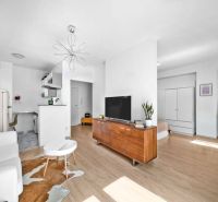 Living room in a 2-room apartment with a TV, the space is bright, flooring with wooden decor.