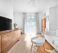 Living room with wood-patterned flooring and furniture in a two-room apartment.