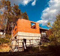 A cottage construction in the recreational area of Nová Kelča surrounded by trees and a blue sky.