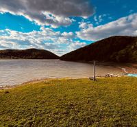 A lake with a sky and hills in the area of Nova Kelca near the recreational cottage zone.