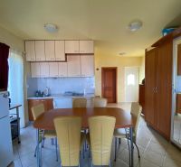 Recreational apartment kitchen with furniture and equipment, including a refrigerator and dining table.