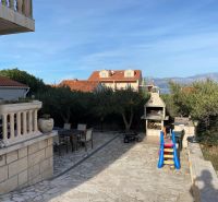 Exterior of a holiday apartment on Brač with a terrace, barbecue, and children's slide.