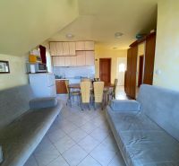 Living area with sofas, kitchen, dining table, and ceramic tiles in a holiday apartment.