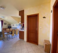 Interior of a holiday apartment with a dining table, kitchenette, and balcony doors.