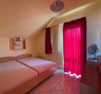 Bedroom in a Holiday Apartment with two beds, a red curtain, and a shelf.