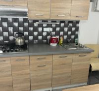 A kitchen unit in a cottage with a sink, gas stove, and marble decor tiles.