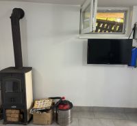 A cottage with tiles, a television, and a supply of wood on a tiled floor.
