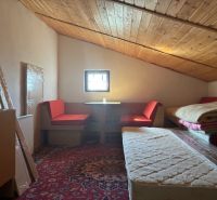 Attic room in a cottage with a wooden ceiling and seating on a red carpet.