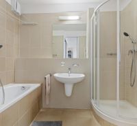 Bathroom with a bathtub, shower, sink, and mirror in a 2-room apartment.