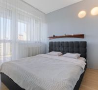 Bedroom in a 2-room apartment with a large bed, curtains, and a floor with a wood decor.