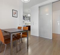 Dining area with brown chairs, wooden decor flooring in a 2-room apartment.