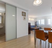Dining area and living room in a two-room apartment with wood-patterned flooring.