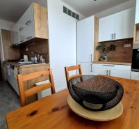 A kitchen in a 3-room apartment with wooden decor and white cabinets.