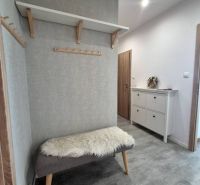 The hallway of a 3-room apartment with a bench, a coat rack, and a shoe cabinet.