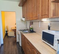 A kitchen with solid wood cabinets and a floor with a wood decor in a 3-room apartment.