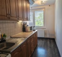 A kitchen in a 3-room apartment with a wooden decor floor and a wooden kitchen unit.