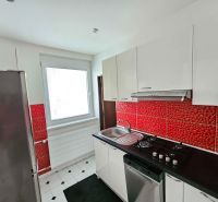 A kitchen with white cabinets and red tiles in a 3-room apartment.