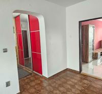 A hallway in a 3-room apartment with red cabinets and a brown floor.