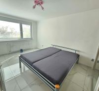 Bedroom with a large bed and white walls in a 3-room apartment, light ceramic floor.