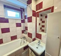 A bathroom in a three-room apartment with square tiles and a bathtub.