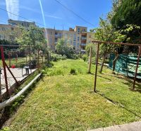 The garden of a family house on Hurbanova Street in Trenčín with greenery and a chair.