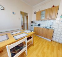 A kitchen in a family house with a wooden decor floor, a dining table, and a kitchen unit.