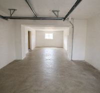 A spacious room in a family house with white walls and a concrete floor.