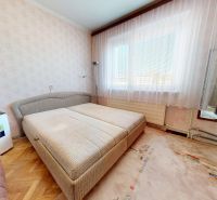 Bedroom in a family house with wallpaper, double bed, mirror, and floor with wooden decor.