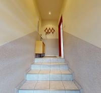 A hallway in a family house with tiles, furniture, and a wall-mounted coat rack.