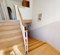 A staircase with a wooden decor floor in a family house, complemented by a wooden railing.