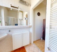 A bathroom in a family house with a sink, shower corner, and white radiator.