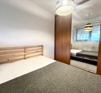 A bedroom in a 3-room apartment with a wooden bed and a built-in wardrobe.