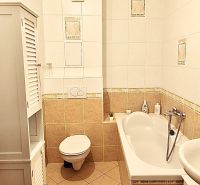 Bathroom with a bathtub and toilet in a 3-room apartment with white tiles.
