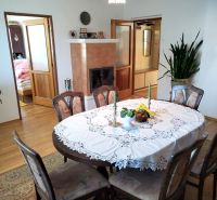 Dining room in a family house with a fireplace and a table with a lace tablecloth.