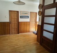 A hallway in a family house with walls of wooden decor and a floor with wooden decor.