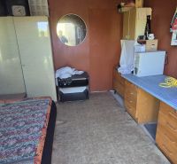 A room in the garden with older furniture, a mirror, and a table with a computer.