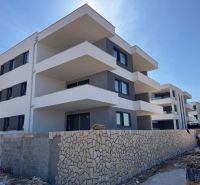 A recreational apartment in Novalja, a three-story building with a stone fence and spacious balconies.