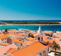 A view of the coastline and rooftops in Novalja, an ideal place for a 2-bedroom apartment.