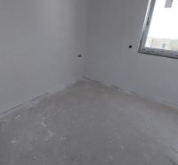 Empty room with gray-white flooring, a window, and white walls in a recreational apartment.