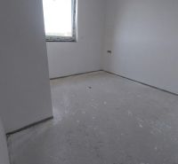 Empty room in a Recreational Apartment with neutral walls and concrete floor.